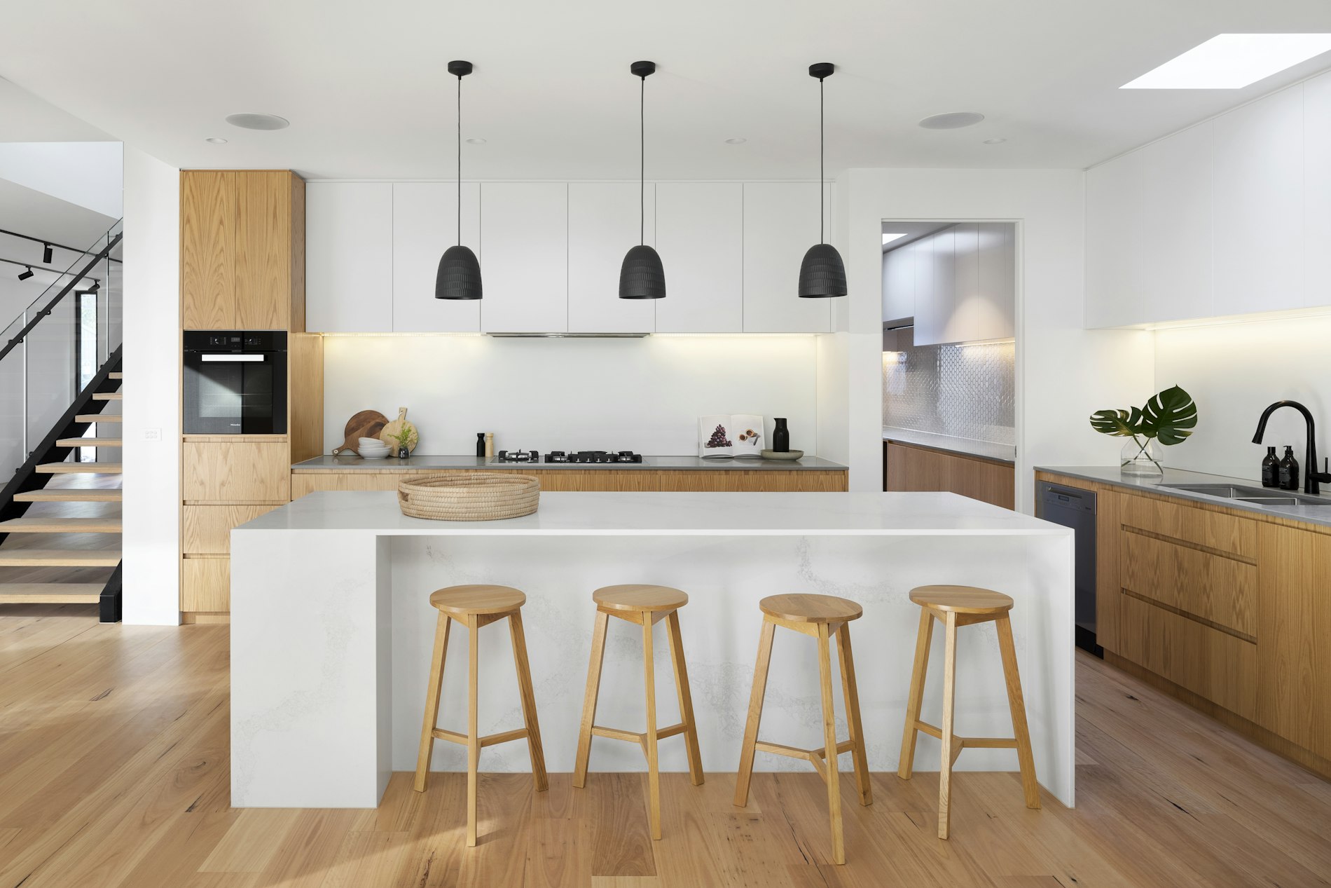 Minimalist chef's kitchen with a large marble island and oak cabinetry