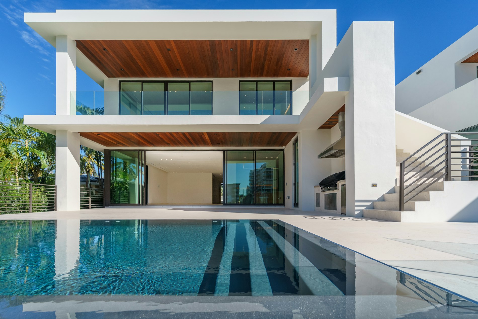 Contemporary luxury home with a swimming pool and floor-to-ceiling glass, at dusk